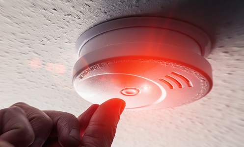 Hand testing a smoke alarm