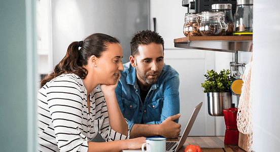 Young Caucasian couple looking at a laptop together to choose a new boiler