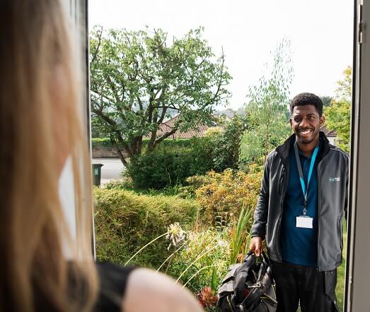 Engineer smiling whilst standing outside a property